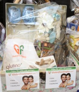 gift package including two champagne glasses and Glutino packaged treats, two flyers in front with a smiling couple advertising Gluten Free Singles