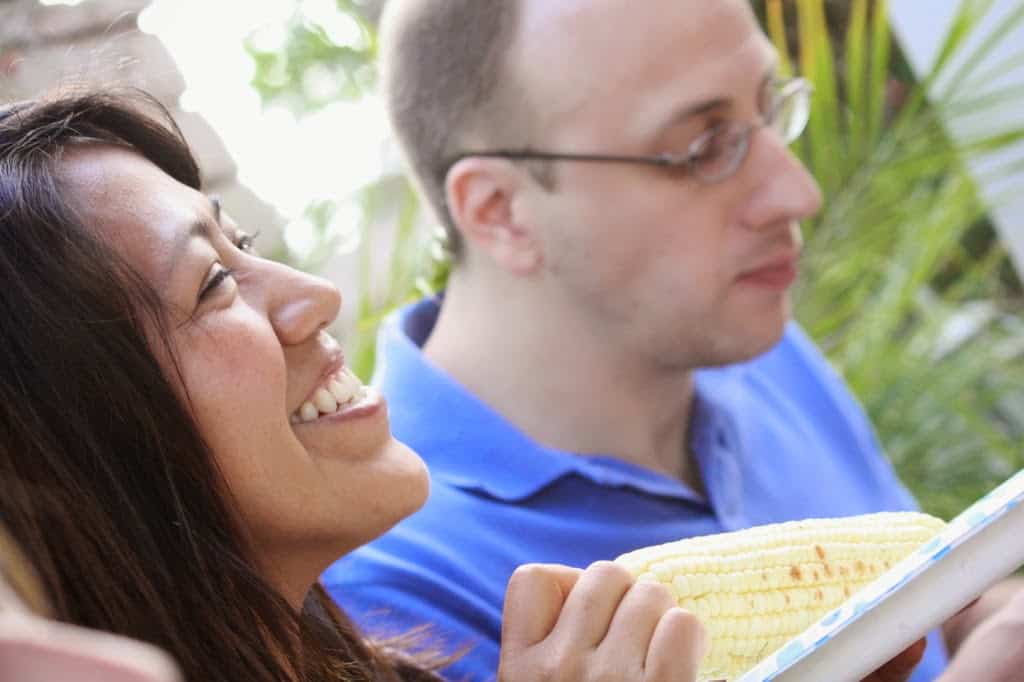woman smiling and eating corn at a bbq