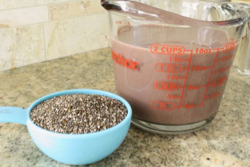 aqua dry measuring cup filled with chia seeds and glass liquid measuring cup with two cups of chocolate almond milk