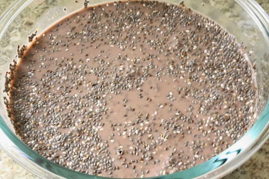 chia seeds floating/gathering on the top of chocolate almond milk in a glass bowl