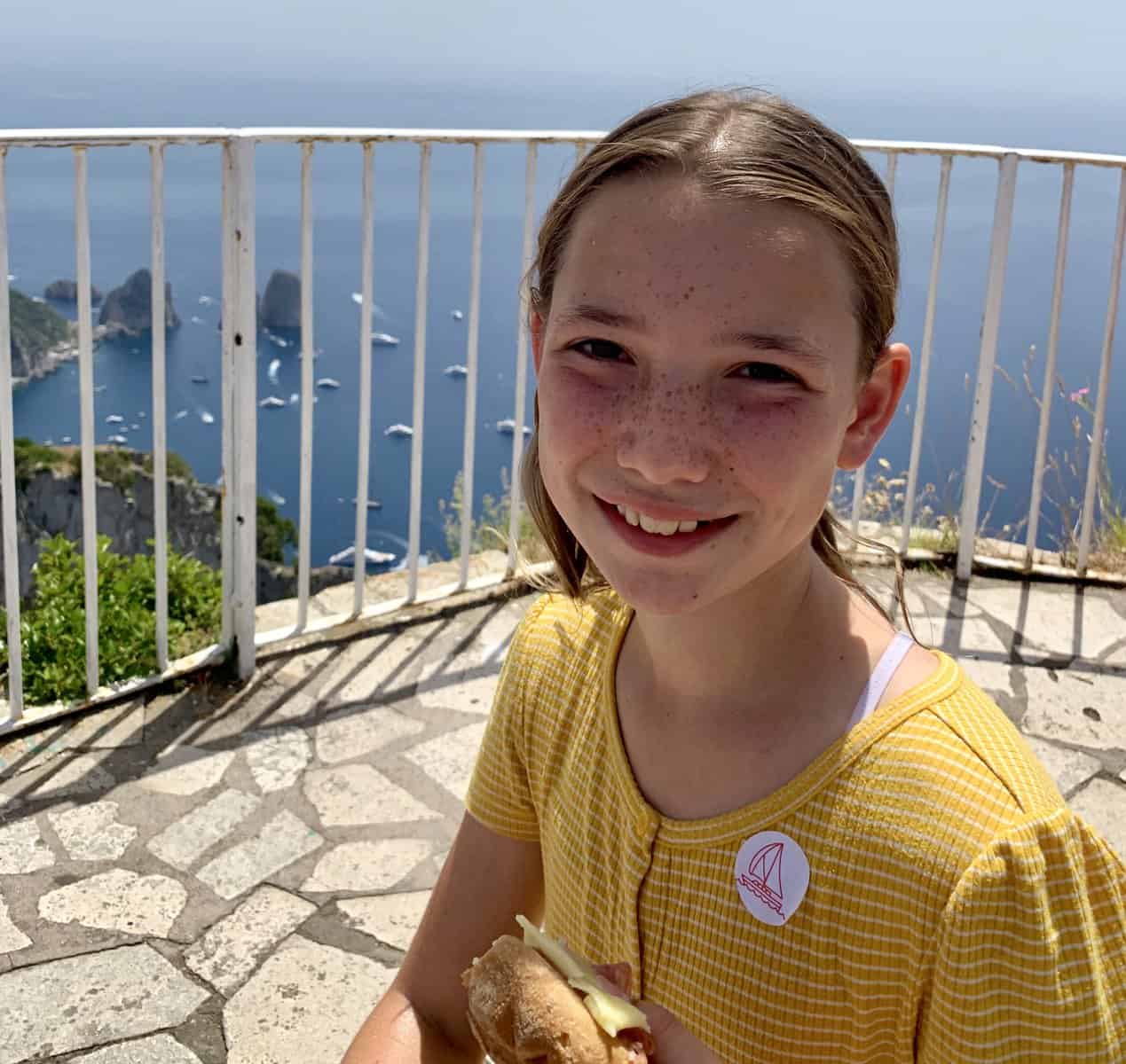 Miss E enjoying a gluten-free Italian sandwich at the top of Anacapri with the sea in the background