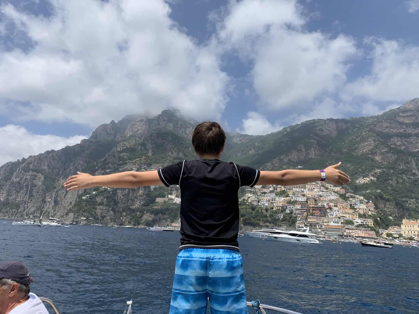 CJ arms wide (titanic-style) at the bow of the boat overlooking the Amalfi Coast