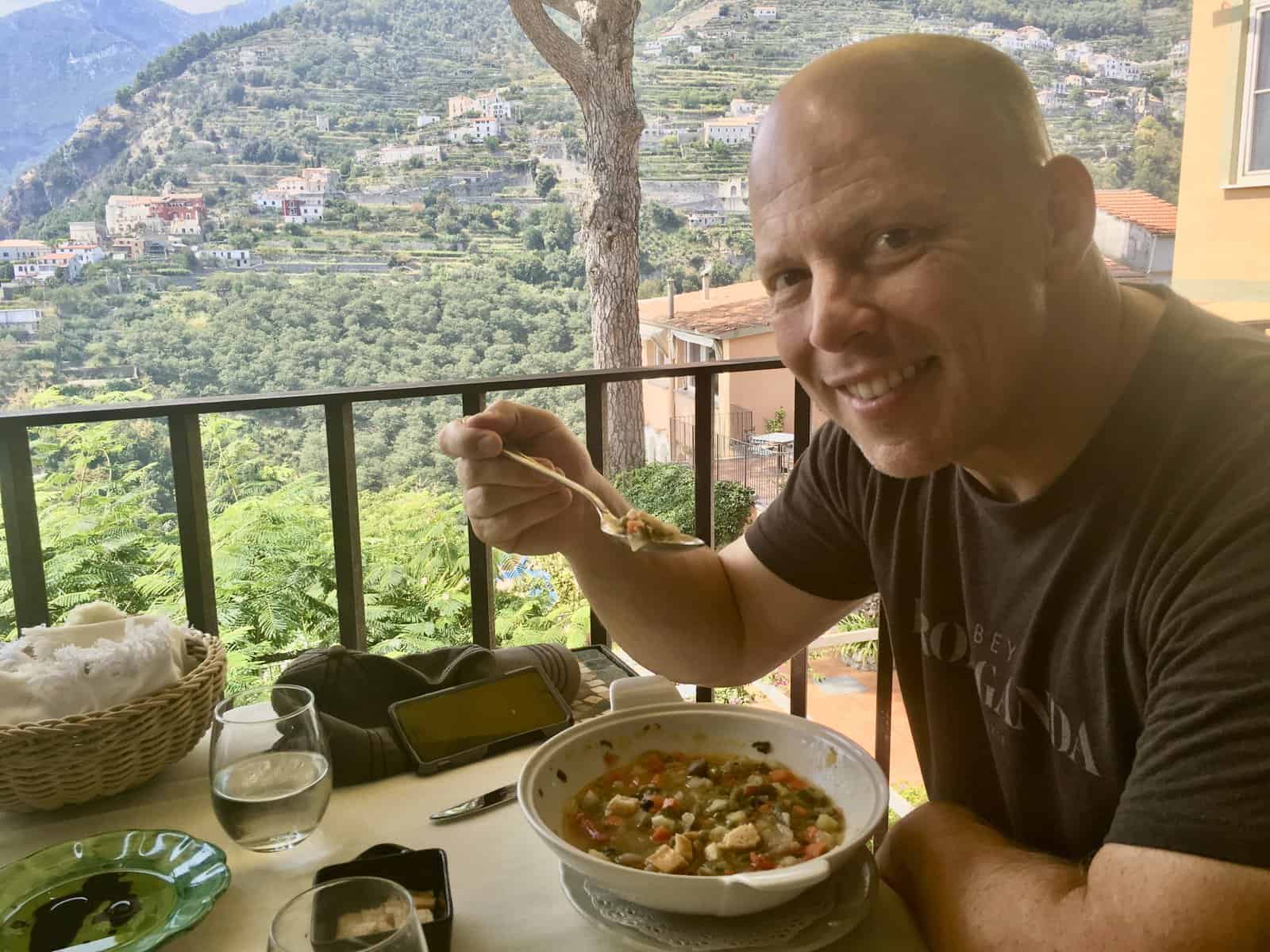 Dave eating gluten-free Italian soup with terraced gardens in the background