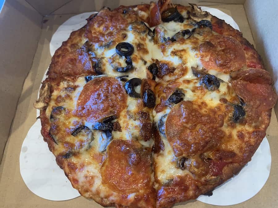 gluten-free pizza in a box with cheese, pepperoni and black olives