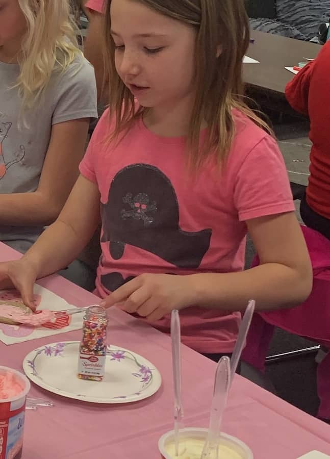 Miss E decorating a gluten-free Valentine cookie with gluten-free sprinkles, at school