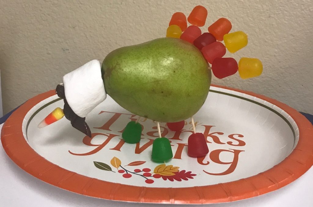 turkey made of: pear, gum drop feet and feathers, toothpicks to hold candy in place, marshmallow head, raisin eyes, candy corn beak and gluten-free licorice waddle