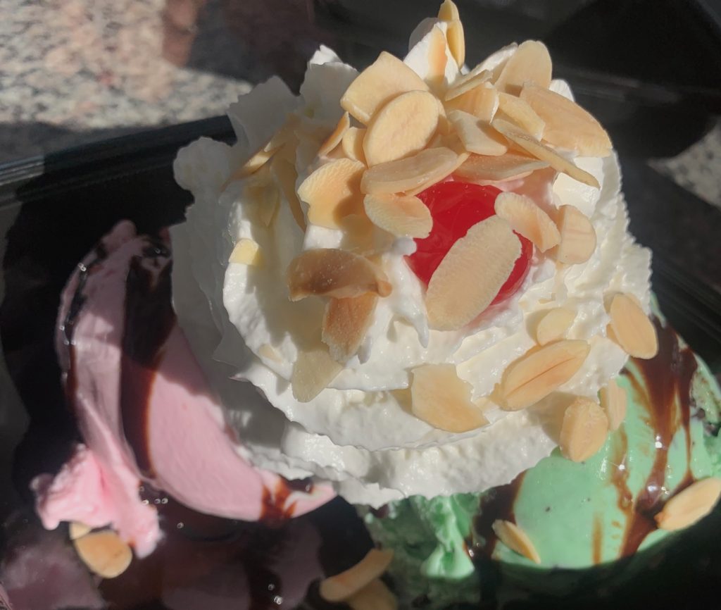 strawberry and mint chip ice cream sundae, topped with whipped cream, nuts an a cherry