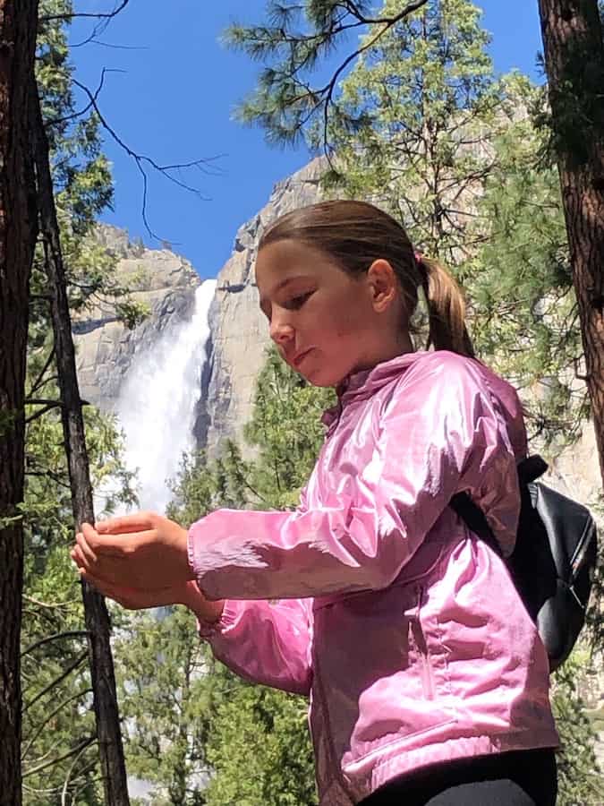 Miss E cupping her hands creating the illusion of catching the water from Yosemite Falls, which is way in the background
