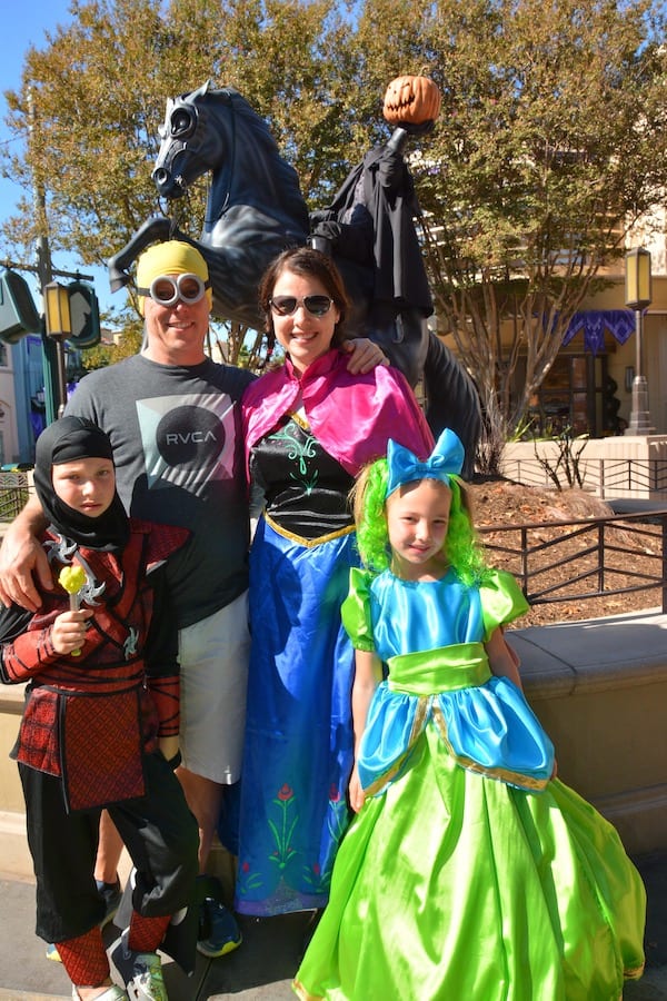 CJ (ninja costume), Dave (minion costume), Heather (Princess Anna costume) and Miss E (Drizella costume) in front of a headless horseman statue