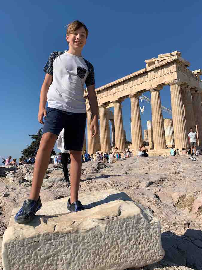 CJ standing on a rock in front of the Greek Parthenon