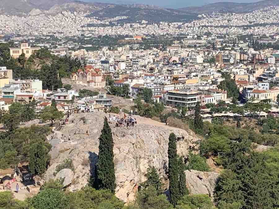 View of Mars Hill from a distance, people on top, the city of Athens in the background