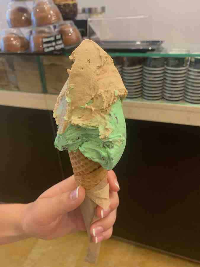 two scoops of ice cream (light brown and green) on a gluten-free cone