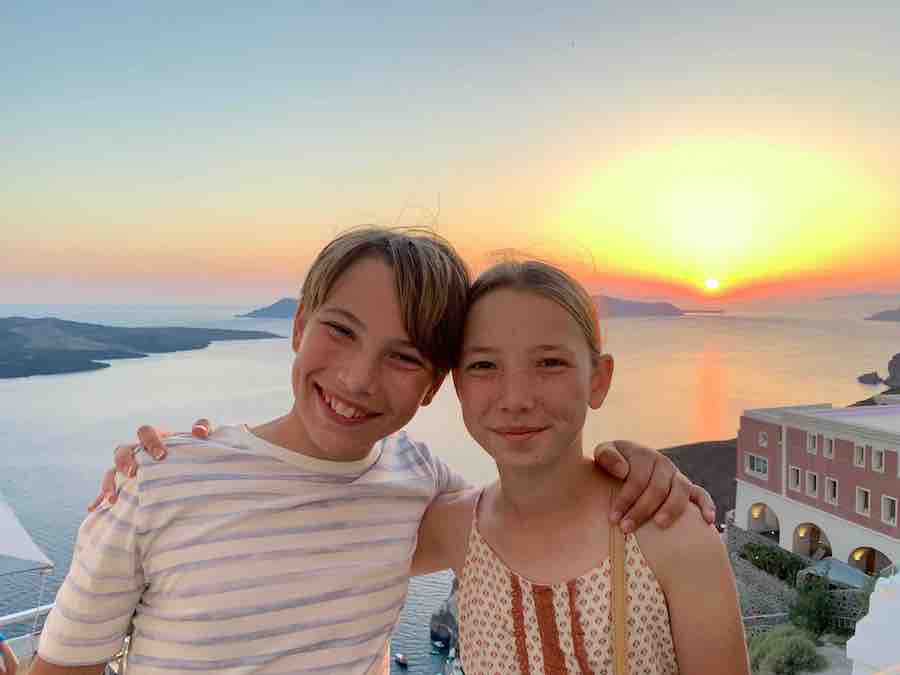 CJ and Miss E smiling with the Santorini caldera sunset in the background