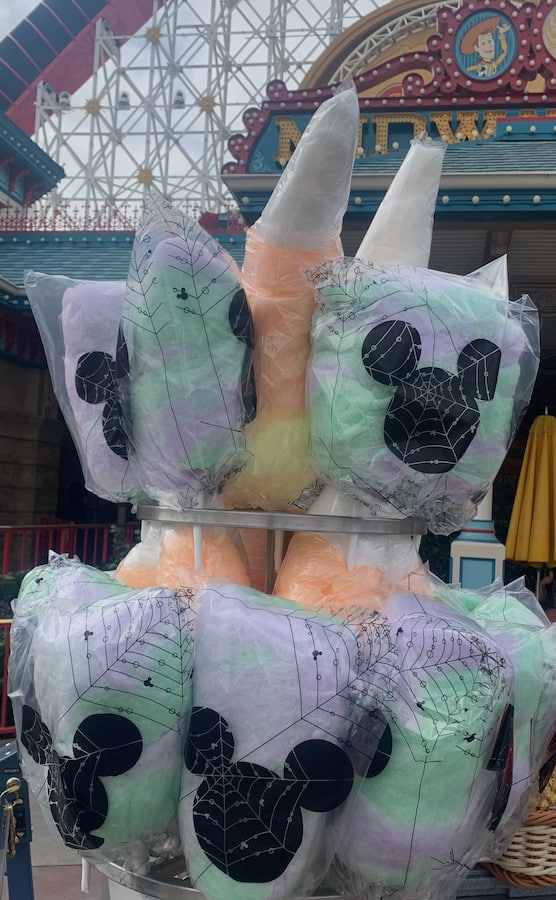 Halloween cotton candy on display, purple and orange ones in bags with Mickey Mouse heads with spider web designs, and others shaped like candy corn