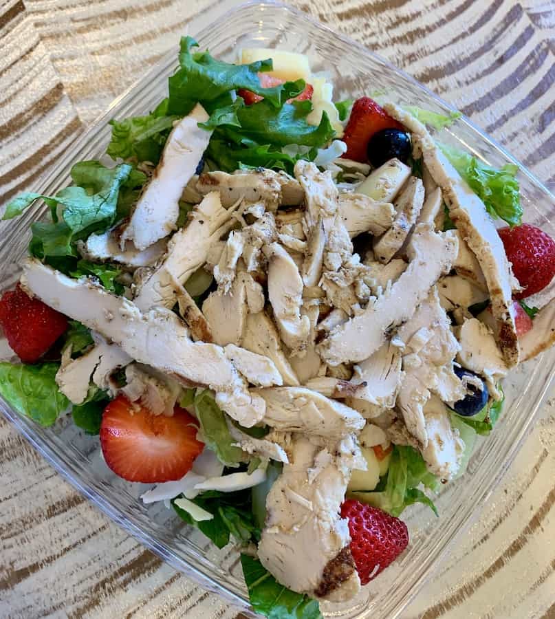 salad in a plastic container with lettuce, strawberries and sliced grilled chicken