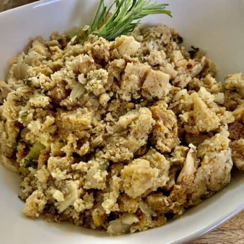 gluten-free stuffing in a white oval bowl with a sprig of rosemary