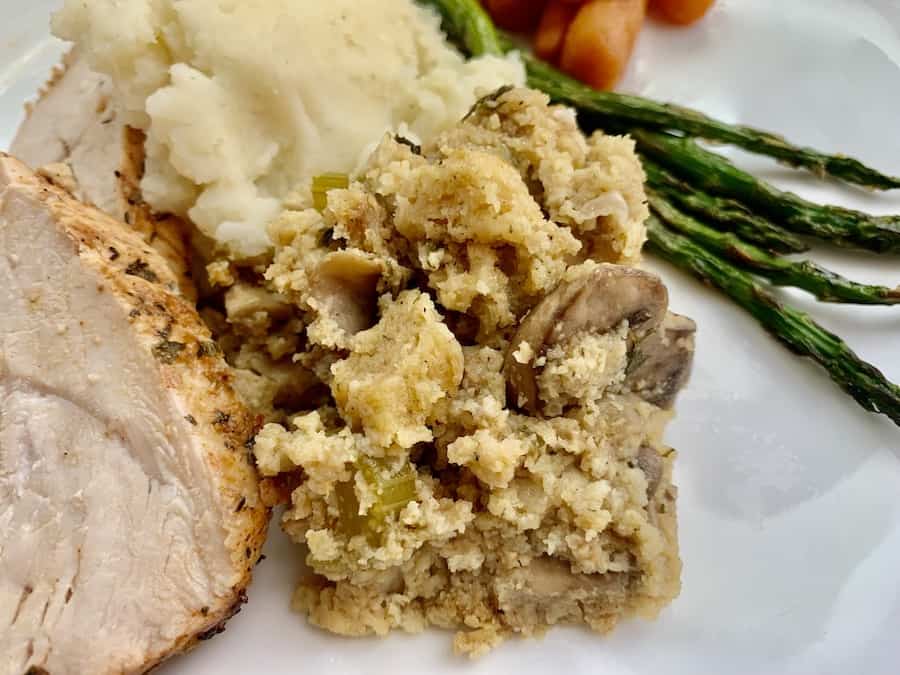 gluten-free stuffing on a plate with turkey, mashed potatoes, carrots, and asparagus