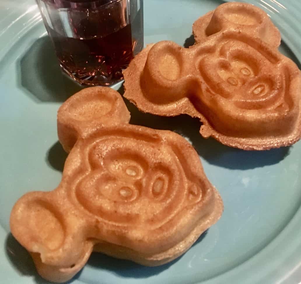 gluten-free dining at Disneyland with two gluten-free mickey waffles and syrup (in a small cup) on a blue plate