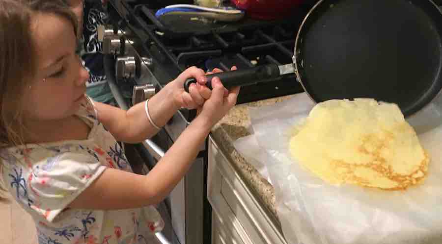 Miss E placing a cooked gluten-free crepe on wax paper