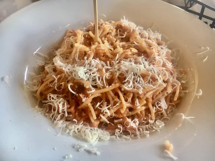 gluten-free spaghetti bolognese, sprinkled with parmesan, in a white bowl