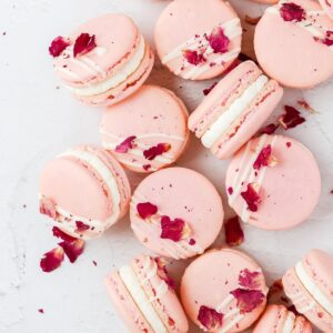 pink macaroons, scattered on a counter with rose petals