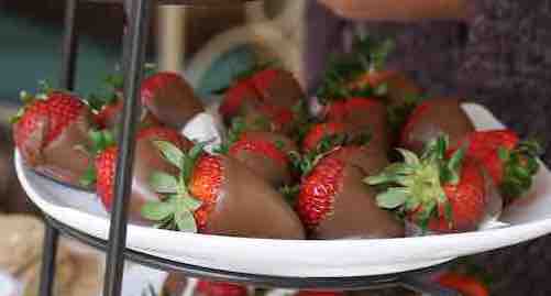 gluten-free chocolate-covered strawberries on a white plate and stand