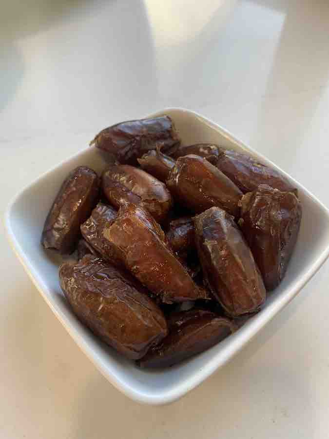 a small white bowl of smaller Deglet Noor dates