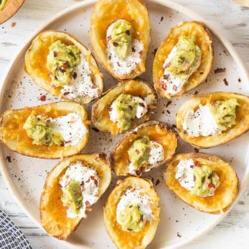 plate of potato skins with guacamole and sour cream toppings