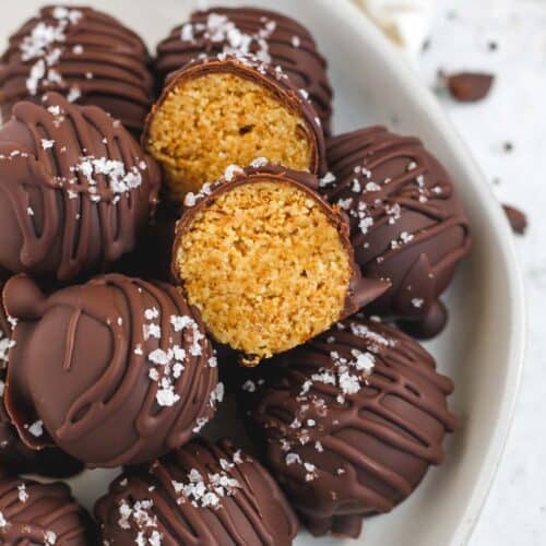 bowl of peanut butter chocolate truffles, one is cut open to reveal peanut butter inside