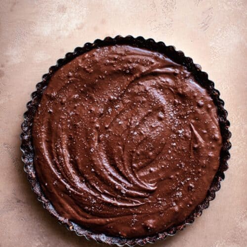 chocolate tart in a black tart pan on a counter