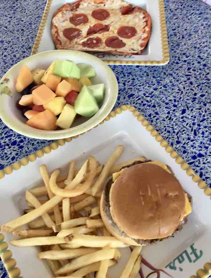 gluten-free pepperoni pizza, bowl of sliced fruit, gluten-free cheeseburger & fries