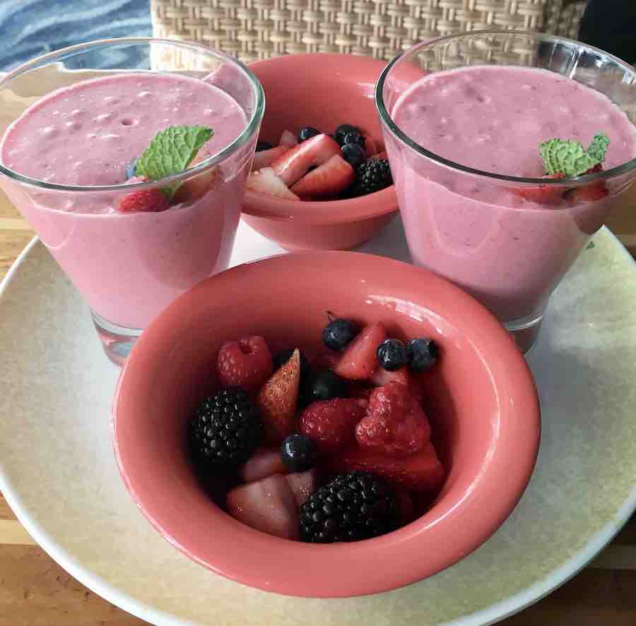 two berry smoothies and two bowls of mixed berries