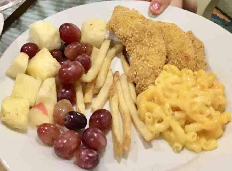 pineapple, grapes, fries, gluten-free Mac & Cheese, and gluten-free chicken tenders on a white plate
