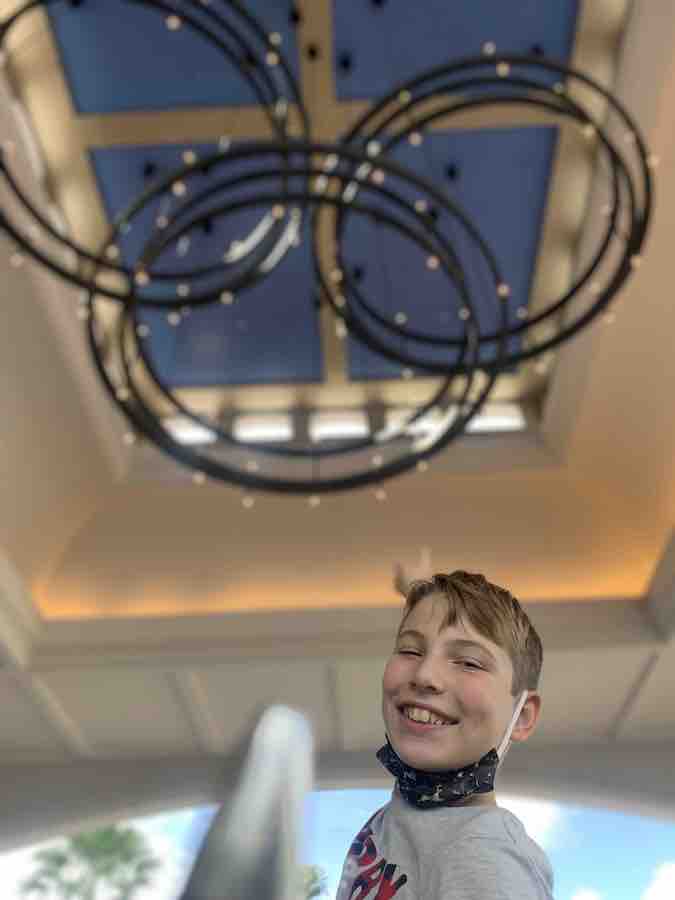 CJ smiling under a "hidden Mickey" chandelier at Disney's Riviera Resort's carport