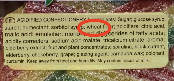 back of a Haribo candy bag focused on on ingredient list translated into English, "wheat" is circled in red