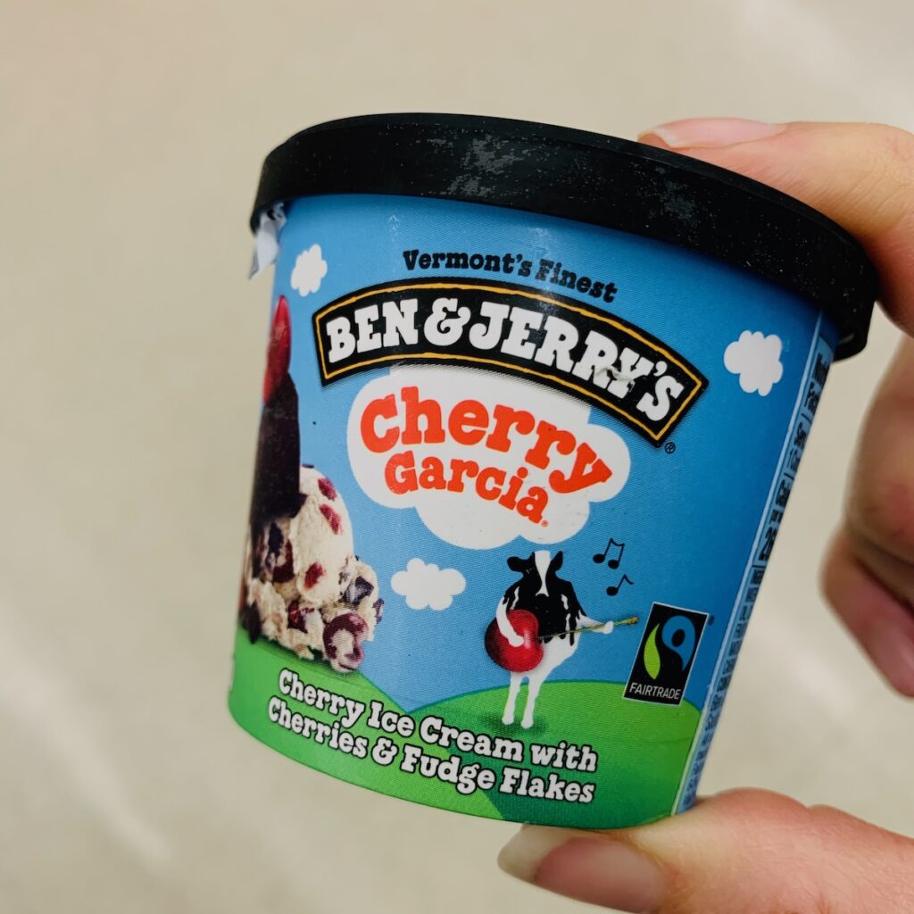 Fingers hold a mini container of Ben & Jerry's Cherry Garcia.