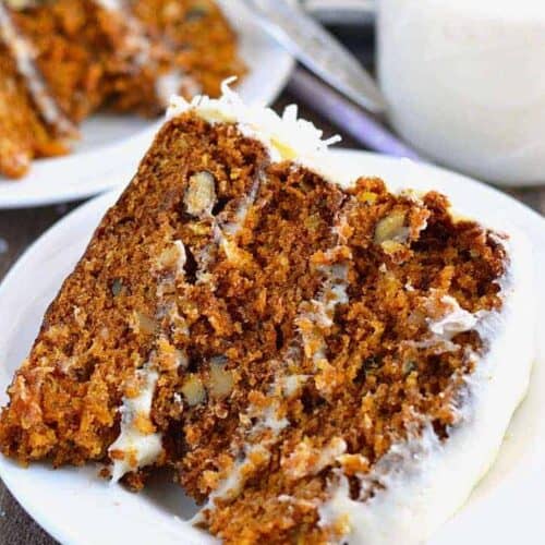 a slice of Gluten Free Carrot Cake, with visibly moist layers, on a white dessert plate