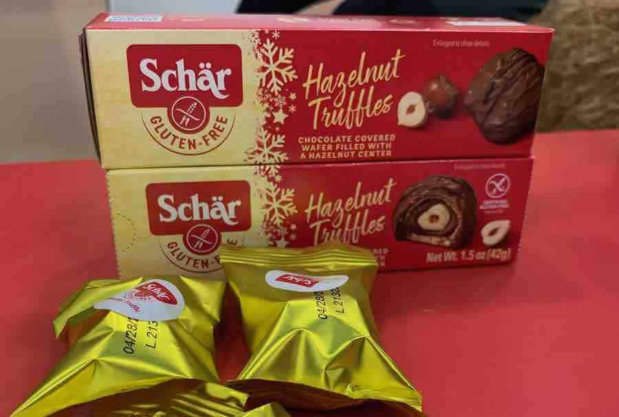 2 packages of Schar hazelnut truffles, and two gold wrapped truffles on the table in front of the packages