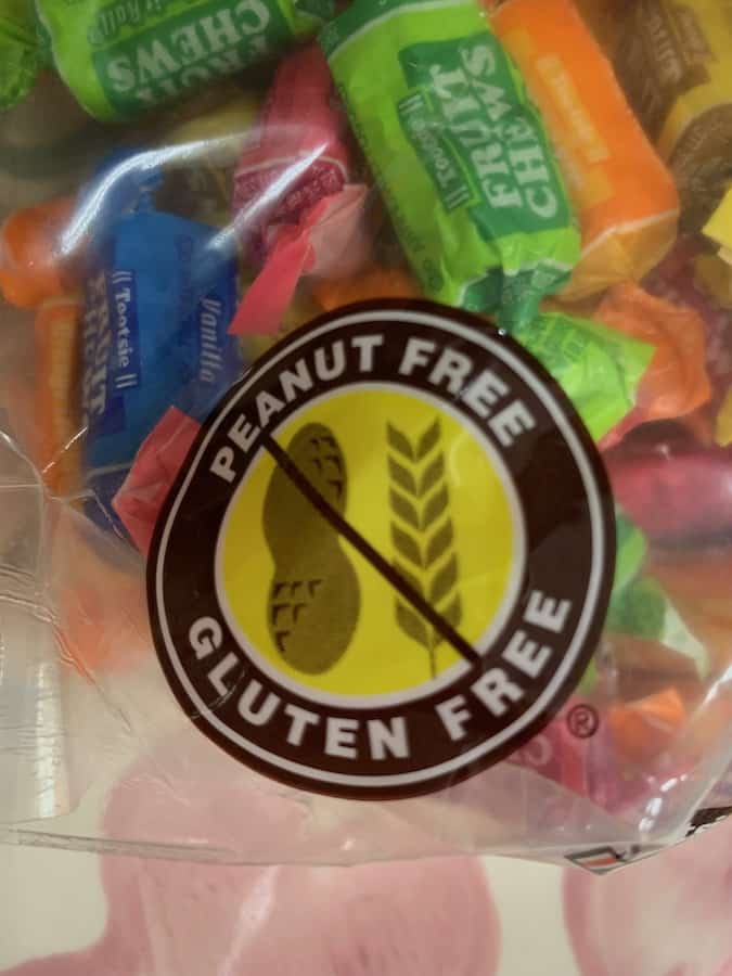 a label showing a symbol with the words "Peanut Free" and "Gluten Free" in a brown circle frame with a yellow circle interiror with a picture of a peanut and wheat crossed out