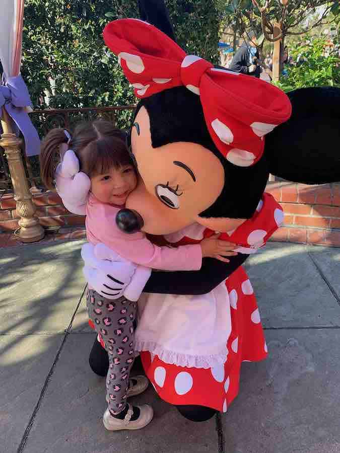 toddler with pig tails and hugging Minnie Mouse