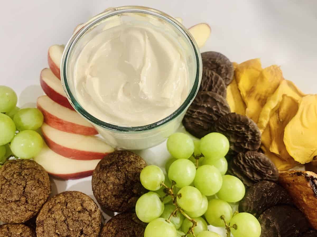 3-ingredient cream cheese caramel apple dip  in a glass bowl/cup for serving, on a white counter