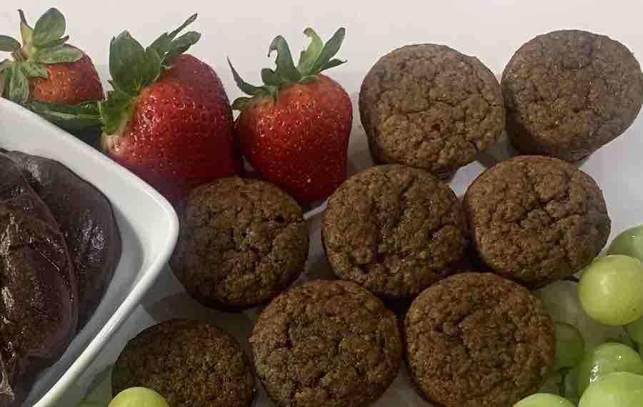 homemade gluten-free mini muffins next to strawberries, grapes and a bowl of chocolate hummus