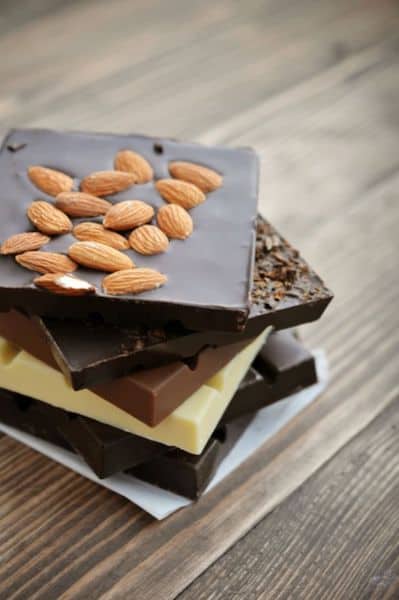 bars of chocolate stacked in a pile (top to bottom): dark chocolate with nuts, dark chocolate, milk chocolate, white chocolate, and dark chocolate