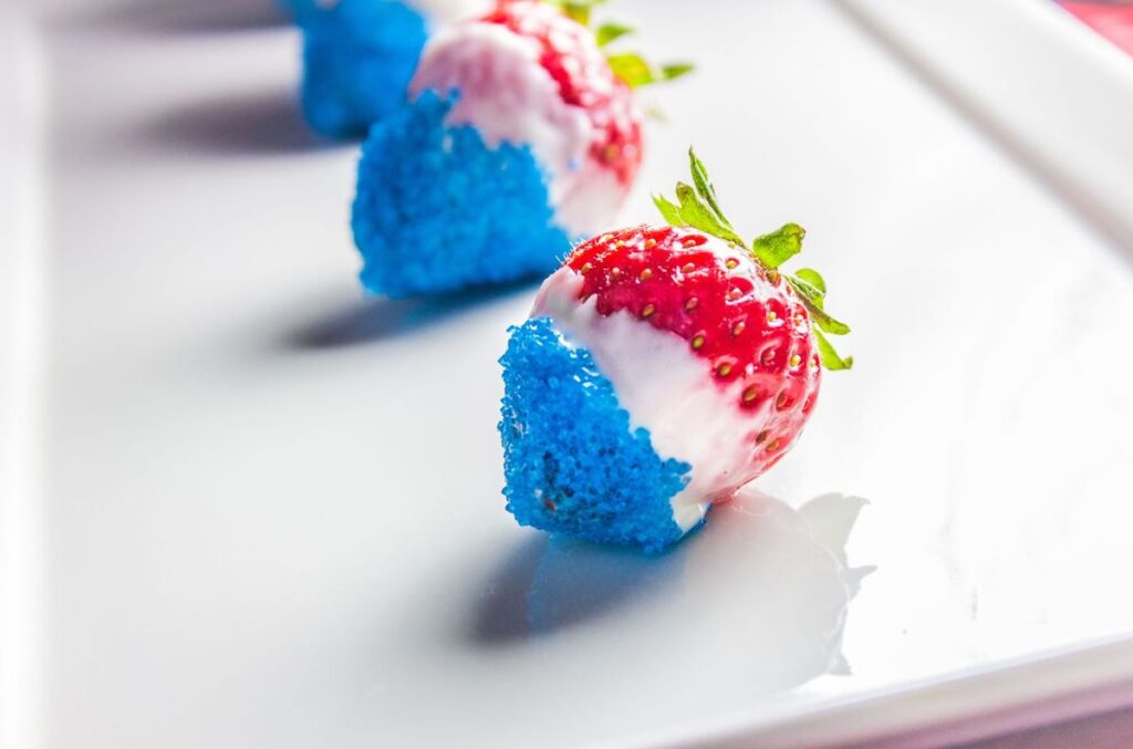 strawberries dipped 2/3 in white chocolate and 1/3 (the tip) in blue sprinkles, creating red, white & blue strawberries
