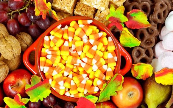fall charcuterie with candy corn, apples, crispy rice treats, chocolate covered pretzels, apples, red grapes and colorful candy leaves