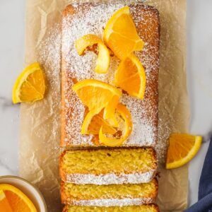 orange olive oil cake with a few slices cut and sliced oranges on top