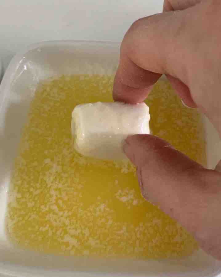 a marshmallow being dipped in melted butter