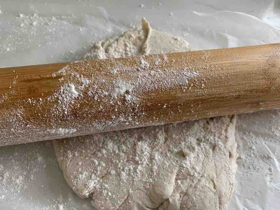 gluten-free pizza dough and a rolling pan, sprinkled with gluten-free flour