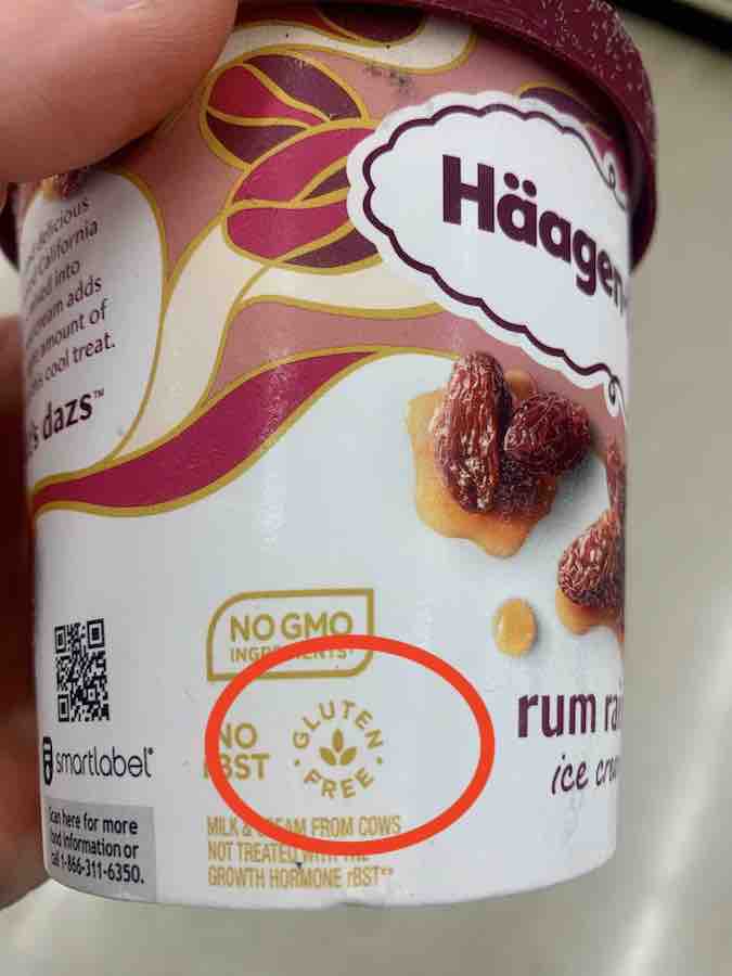 container of haagen-dazs rum raisin ice cream with gluten-free symbol (text gluten-free in a circle around a three leaf image, that appears like the very tip/top of wheat) circled in red