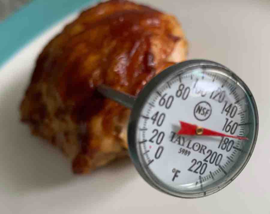 a bbq chicken thigh with a meat thermometer showing 170 degrees